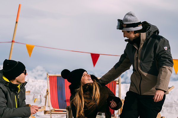 Une femme et deux hommes rigolant ensemble lors d'un moment de détente au ski