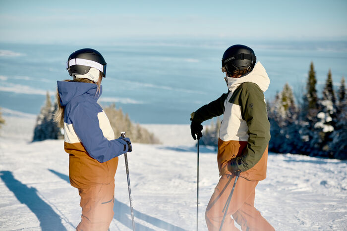 2 personnes de dos, portant une tenue de ski Rossignol. Ils s'apprêtent à dévaler une piste de ski 